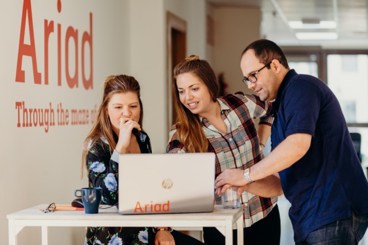 Three coworkers looking at a laptop