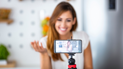 Woman sitting in front of a camera recording a video